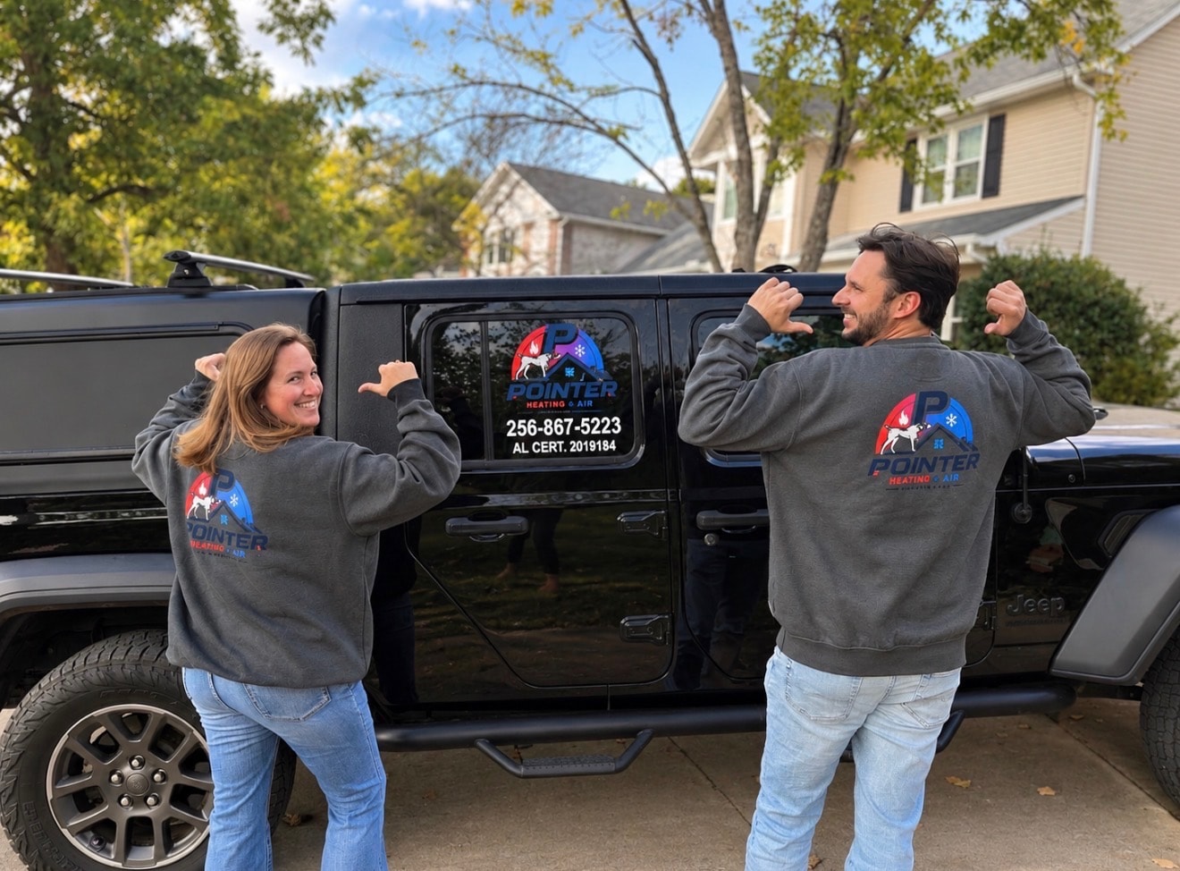 Leah and Clint Rise, co-owners of Pointer Heating & Air, showing off their branded sweatshirts in front of the company Jeep